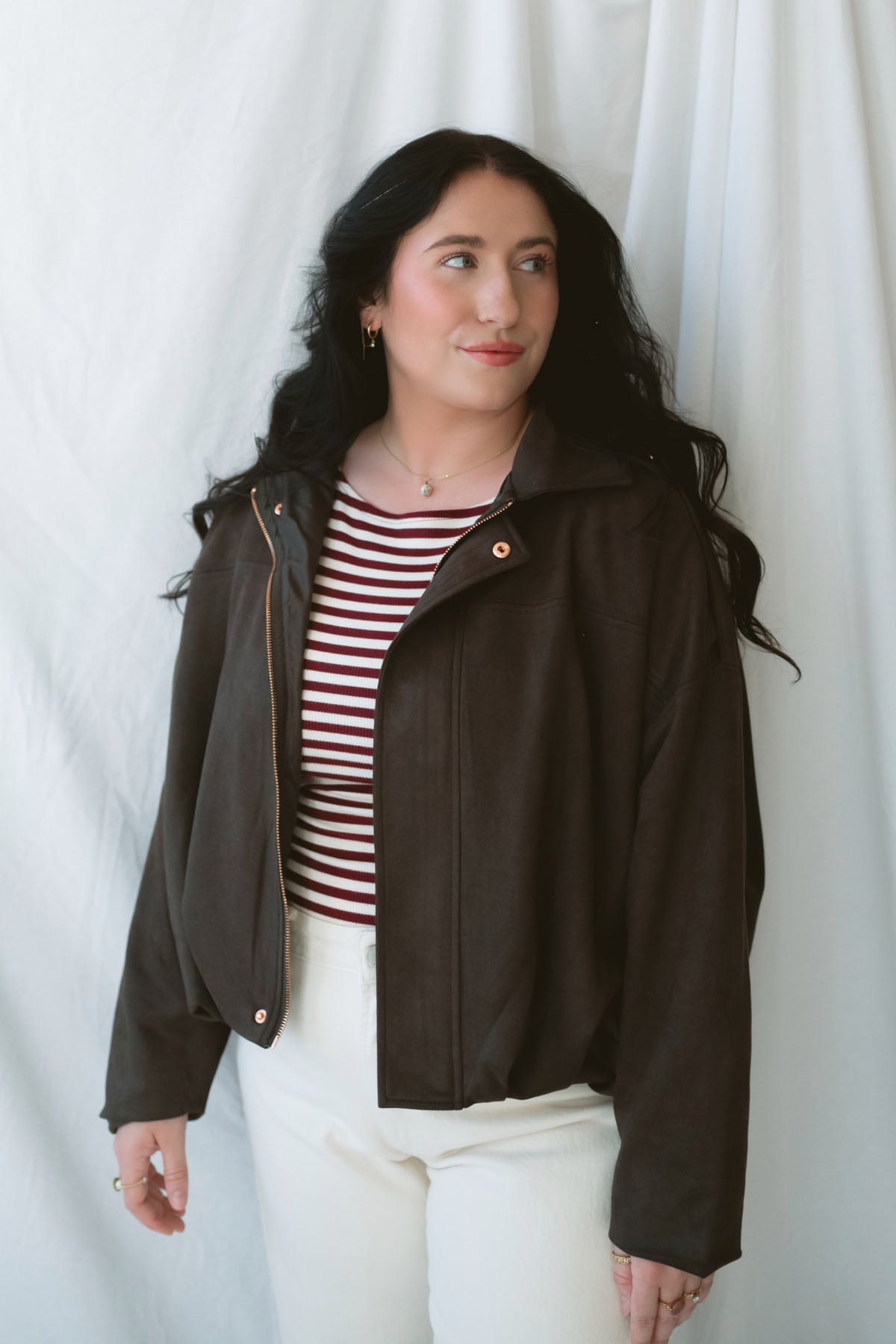 Model is wearing the suede bomber jacket in coffee brown. 