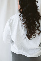 Back view of model wearing the teach embroidered icons sweatshirt.