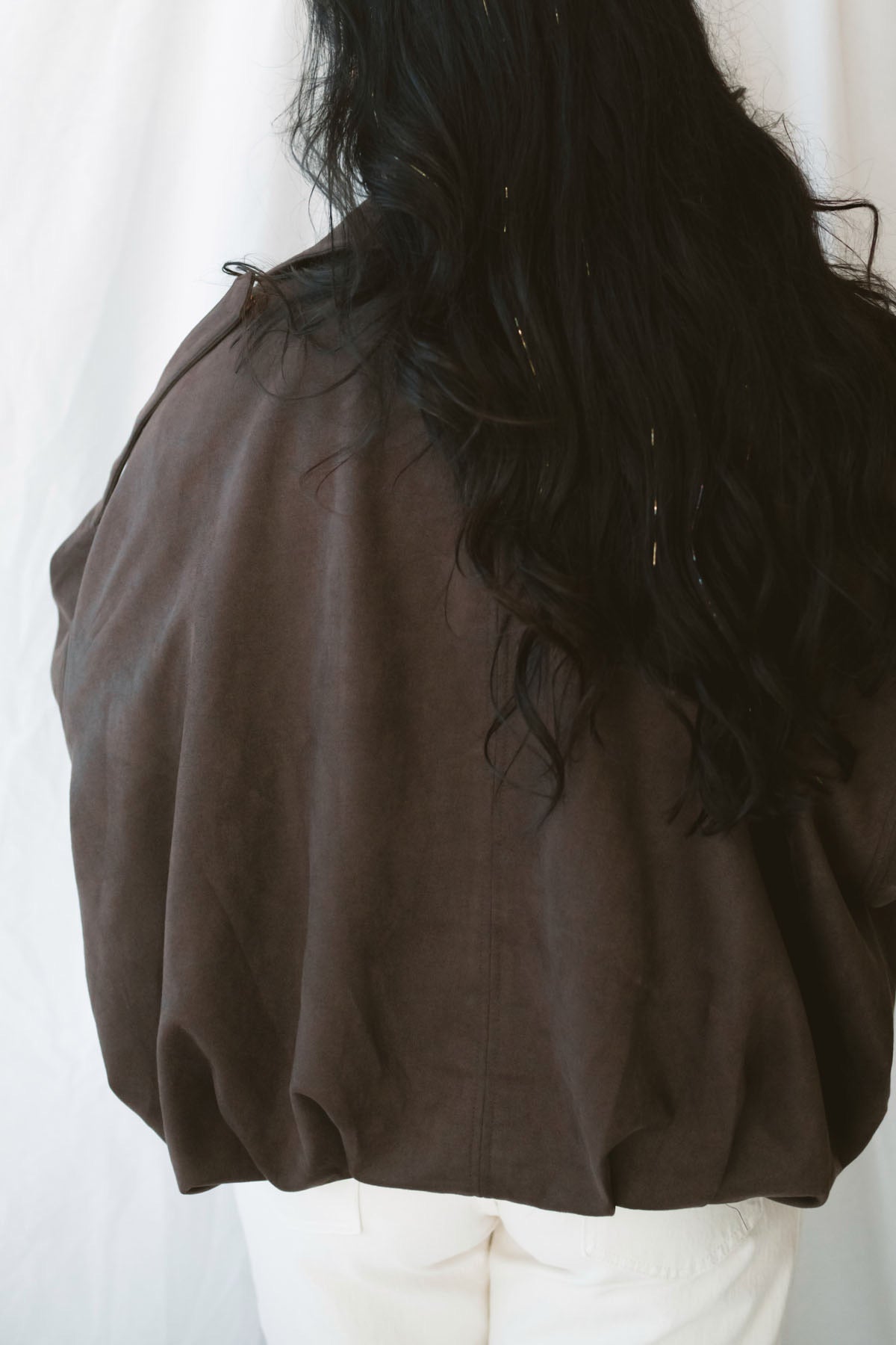 Model is wearing the suede bomber jacket in coffee brown. 