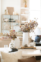The tan two tone eucalyptus stem styled on the dinning room table in white vase. 