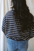 Model wearing striped crew neck sweater with raw edge detail. 