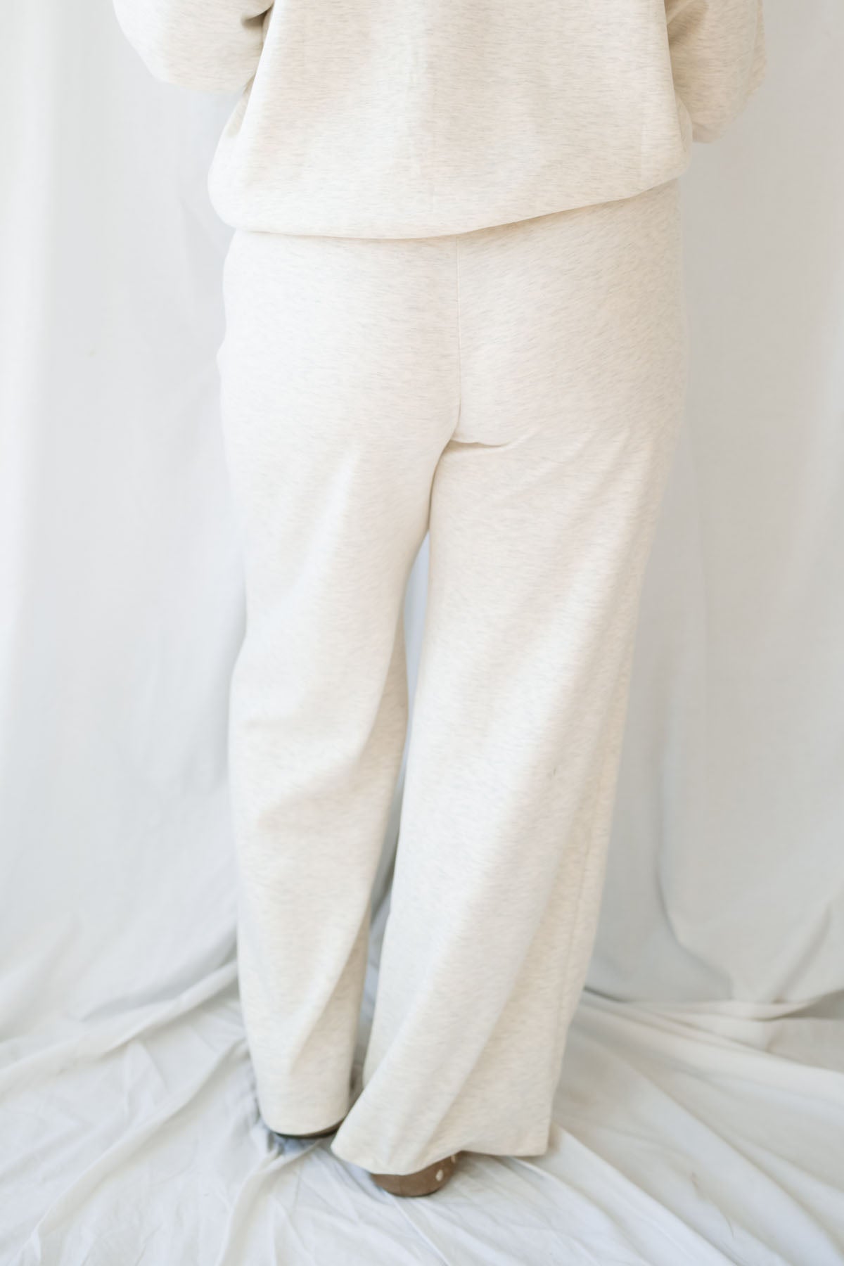 Woman wearing a light beige lounge set with crew neck sweatshirt and drawstring pants on a white background 
