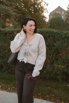 Kayla light taupe knit sweater with a reversible ribbon bow detail, styled with the bow in front.