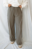 Model wearing the drawstring waist track pants in truffle. 