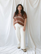Model wearing the oversized v-neck sweater top in terracotta and cream stripes. 