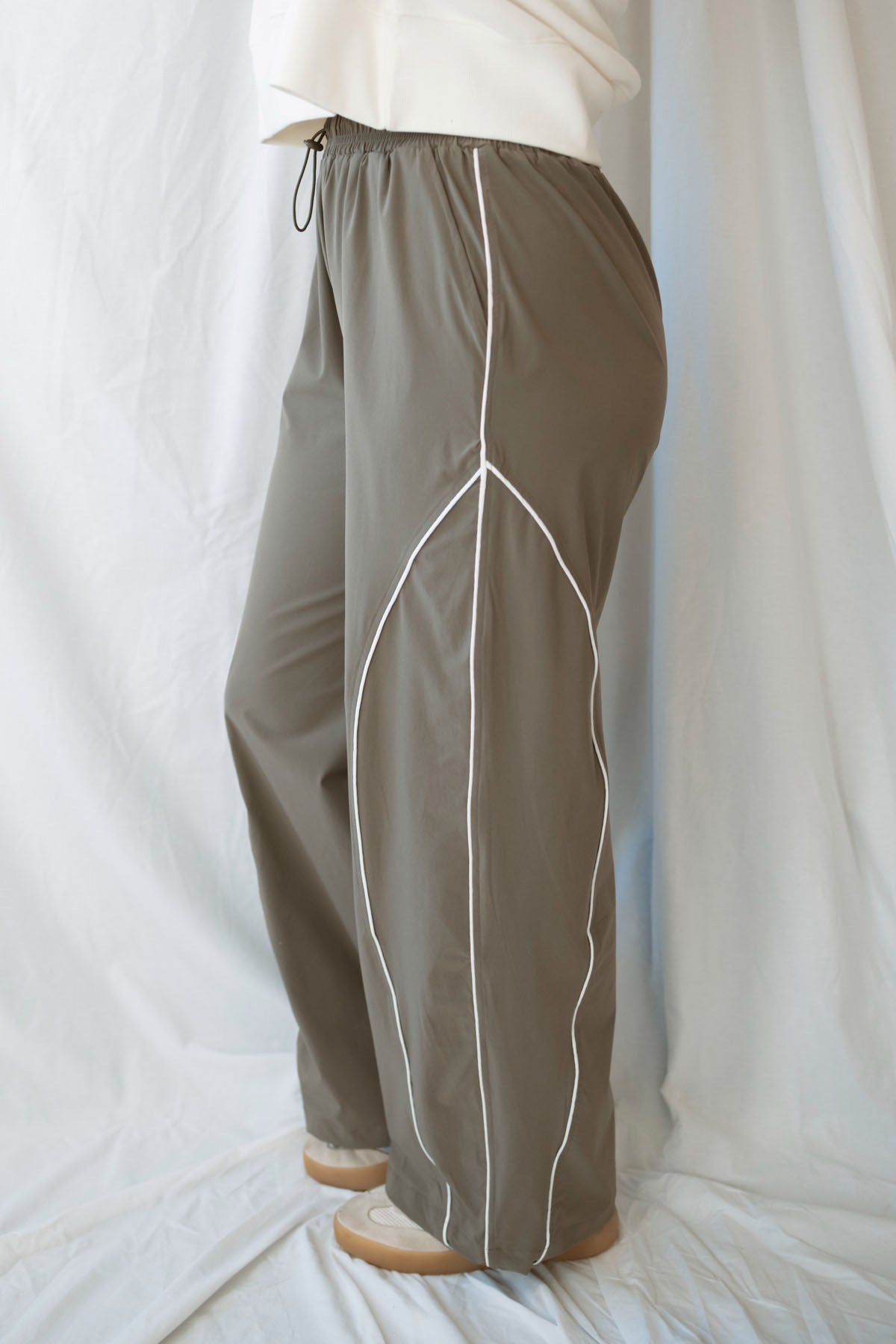 Model wearing the drawstring waist track pants in truffle. 