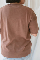Back view of model wearing the boxy fit short sleeve sweater in a rusty rose / sepia color. Model paired the top with jeans and a platform sandal. Wears well through seasons. 