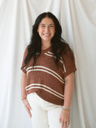 Model wearing the oversized v-neck sweater top in terracotta and cream stripes. 