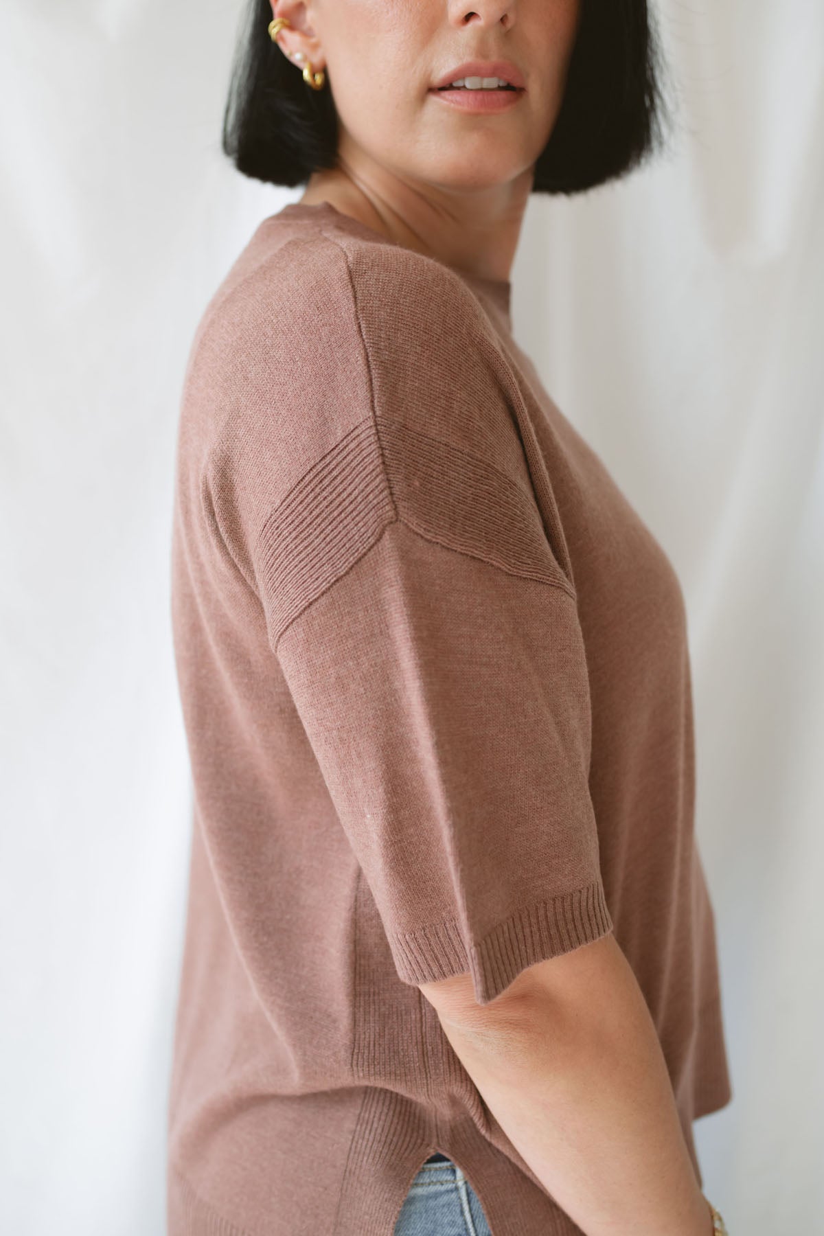 Close up side view of model wearing the boxy short sleeve sweater. Model paired the top with jeans and a platform sandal. Wears well through seasons. 