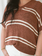Model wearing the oversized v-neck sweater top in terracotta and cream stripes. 