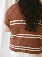 Model wearing the oversized v-neck sweater top in terracotta and cream stripes. 