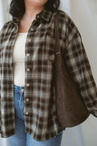 Model is wearing a long sleeve plaid button down. Styled with a square neck neutral tank and jeans.