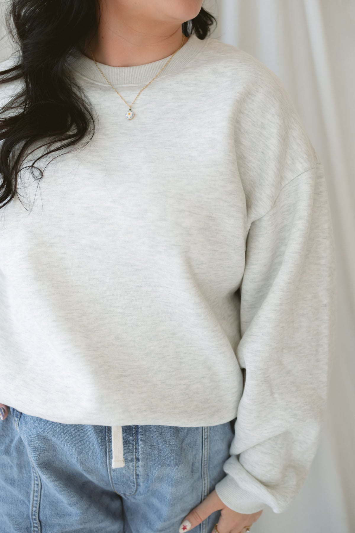 Model wearing the oversized grey crew neck sweatshirt. Model has it styled with a pair of barrel jeans and sneakers for a casual everyday look.