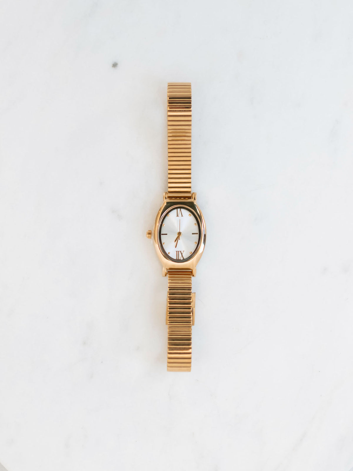 Snake band oval watch sitting on white marble board. 