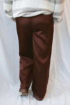 Brown satin wide-leg pants for women featuring delicate lace trim, a mid-waisted silhouette, and a smooth satin finish for elevated everyday styling.