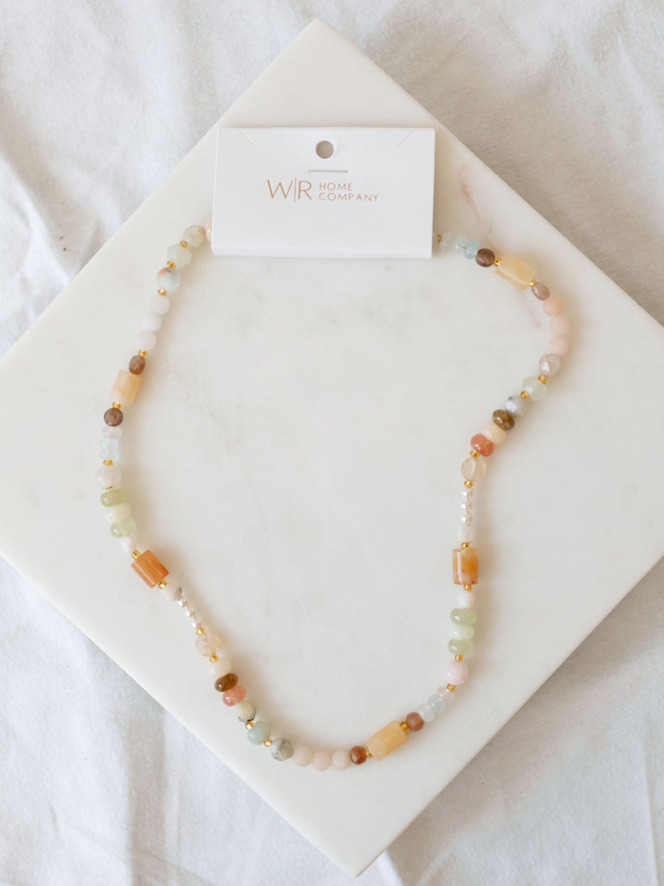 Handmade beaded necklace laying on marble board. 