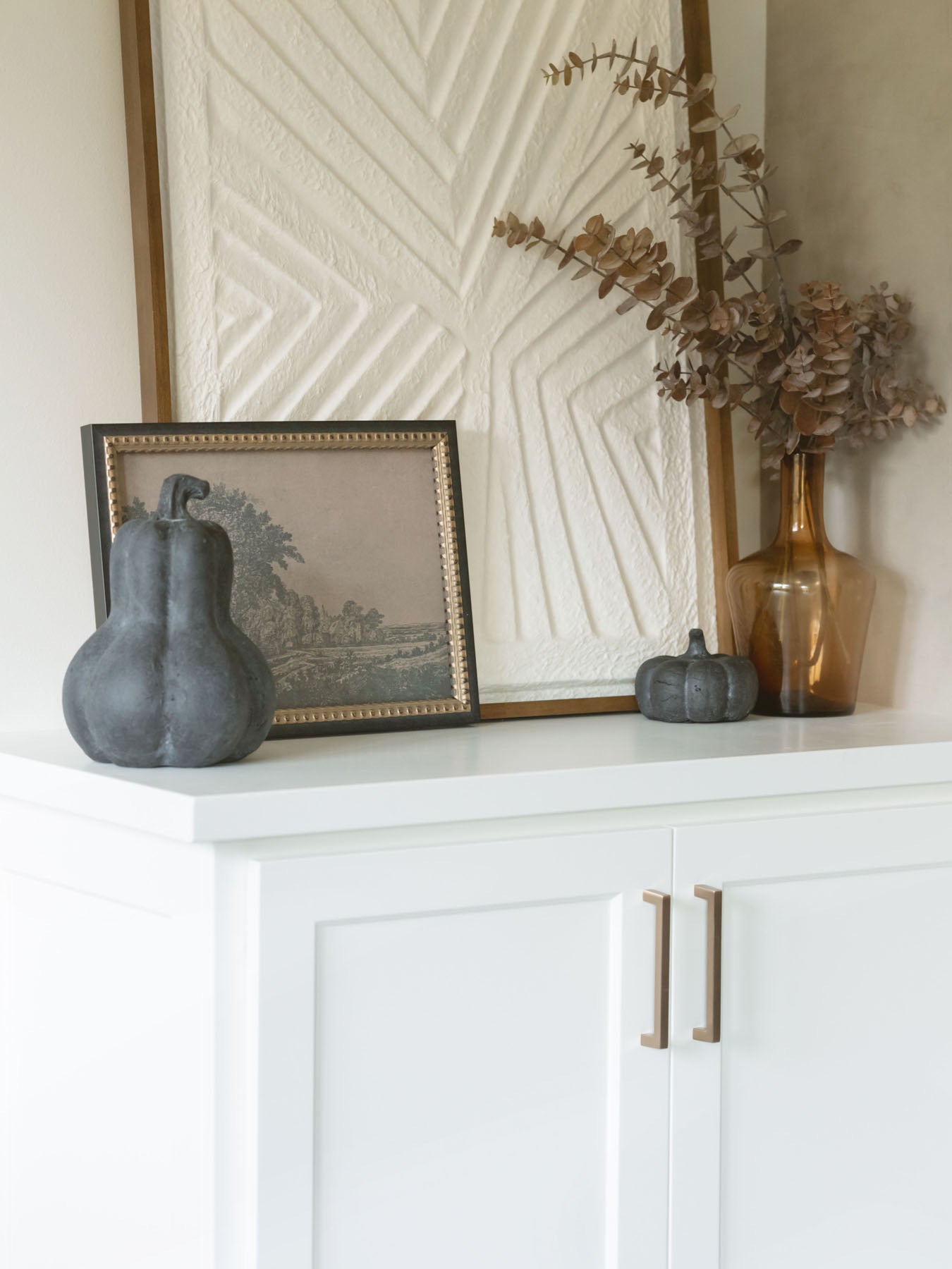 The largest size gourd shape and the smallest size in the pumpkin shape are styled together on a cabinet. Paired with the amber vase for extra warmth. 