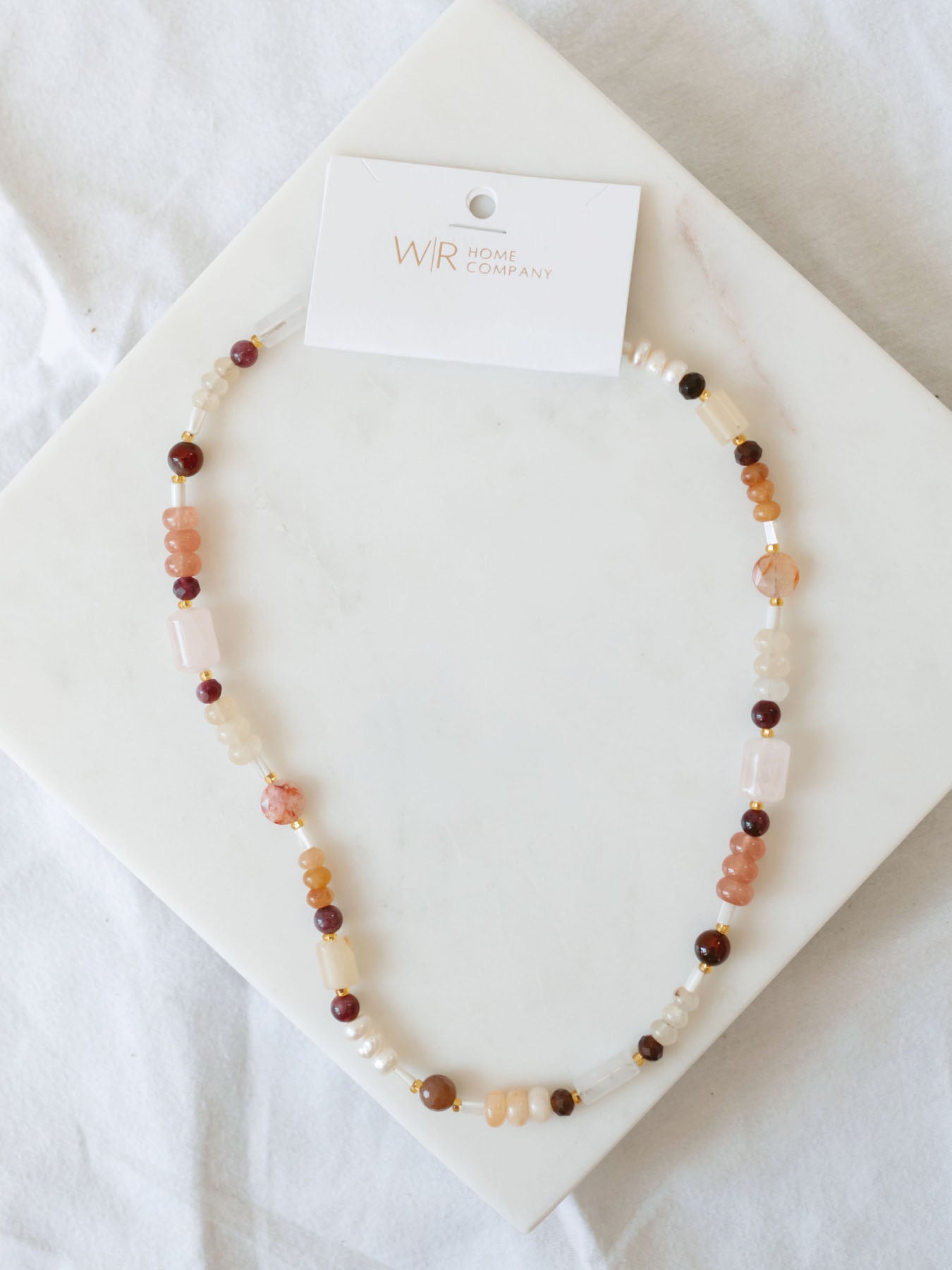 Handmade beaded necklace laying on marble board. 