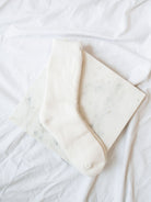 White color boot length socks laying on white marble board.