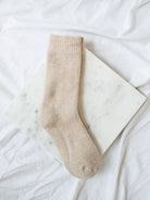 Khaki colored imitation cashmere boot socks laying on a marble board. 