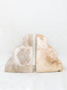 The set of beige marble scalloped edge bookends sitting next to each other with noting between them. 