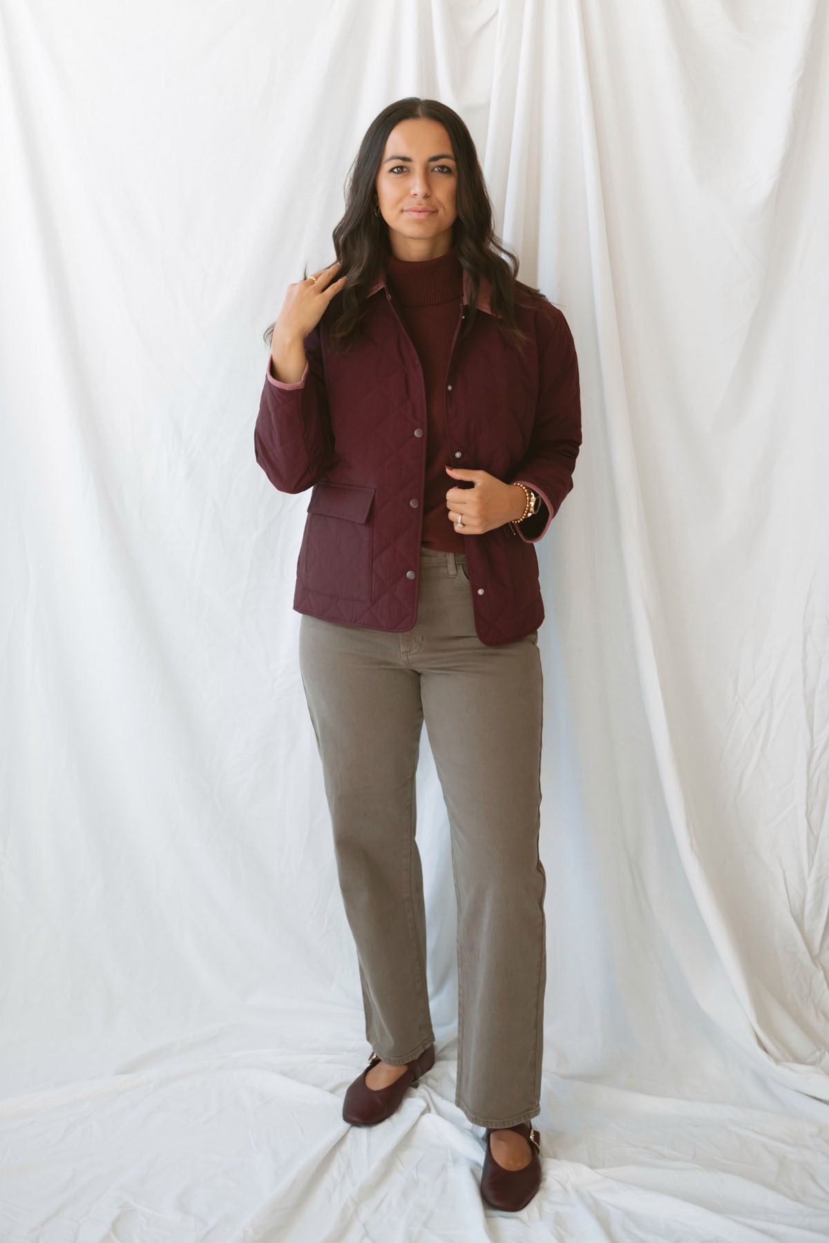 Model is wearing a quilted two tone jacket in burgundy. 