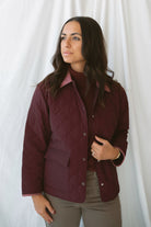 Model is wearing a quilted two tone jacket in burgundy. 