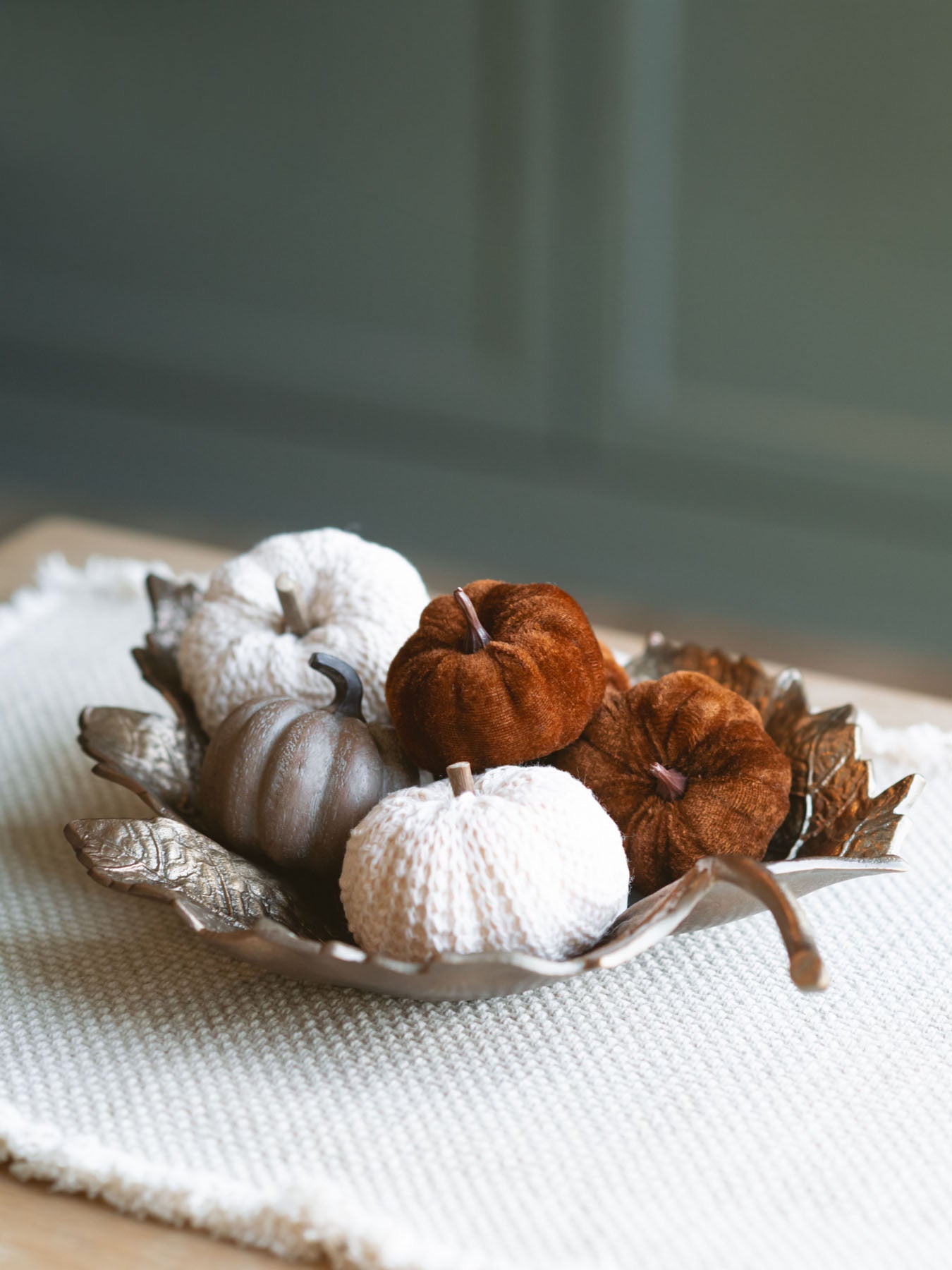 Antique gold leaf dish filled with small textured pumpkins sitting on a shelf. 