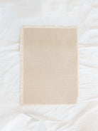 Cotton Beige Placemat with fringe edges laid out on white linen backdrop. 