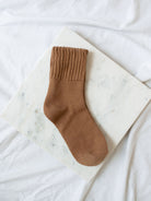Caramel brown crew sock laying on marble board. 