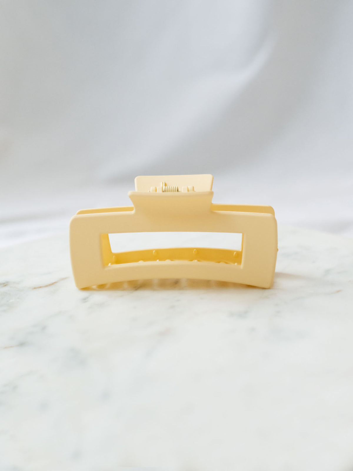 Matte Beige square claw clip sitting on marble board. 
