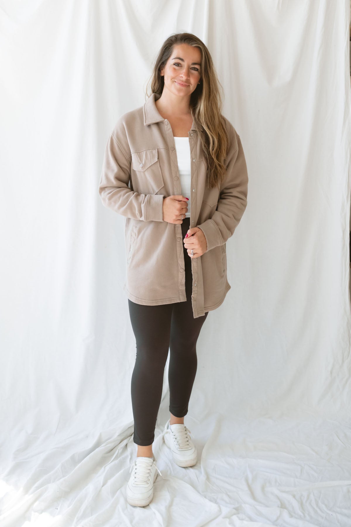 Model is wearing an oversized shacking in the color silken taupe. Model has it styled open with leggings and a tank. 