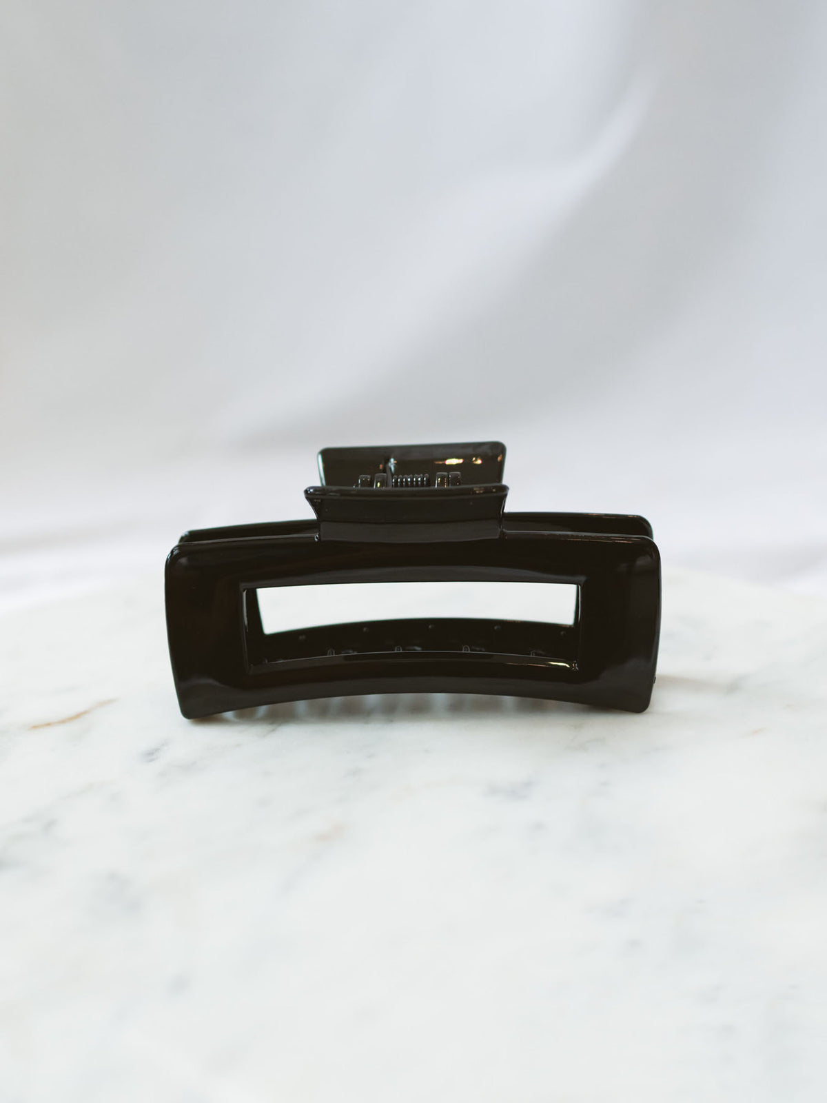 Black square claw clip sitting on marble board. 
