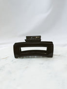 Black square claw clip sitting on marble board. 