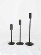 The three sizes of black candle stick holders sitting next to each other going from shortest to tallest. Simple, timeless, and chic home decor option. 