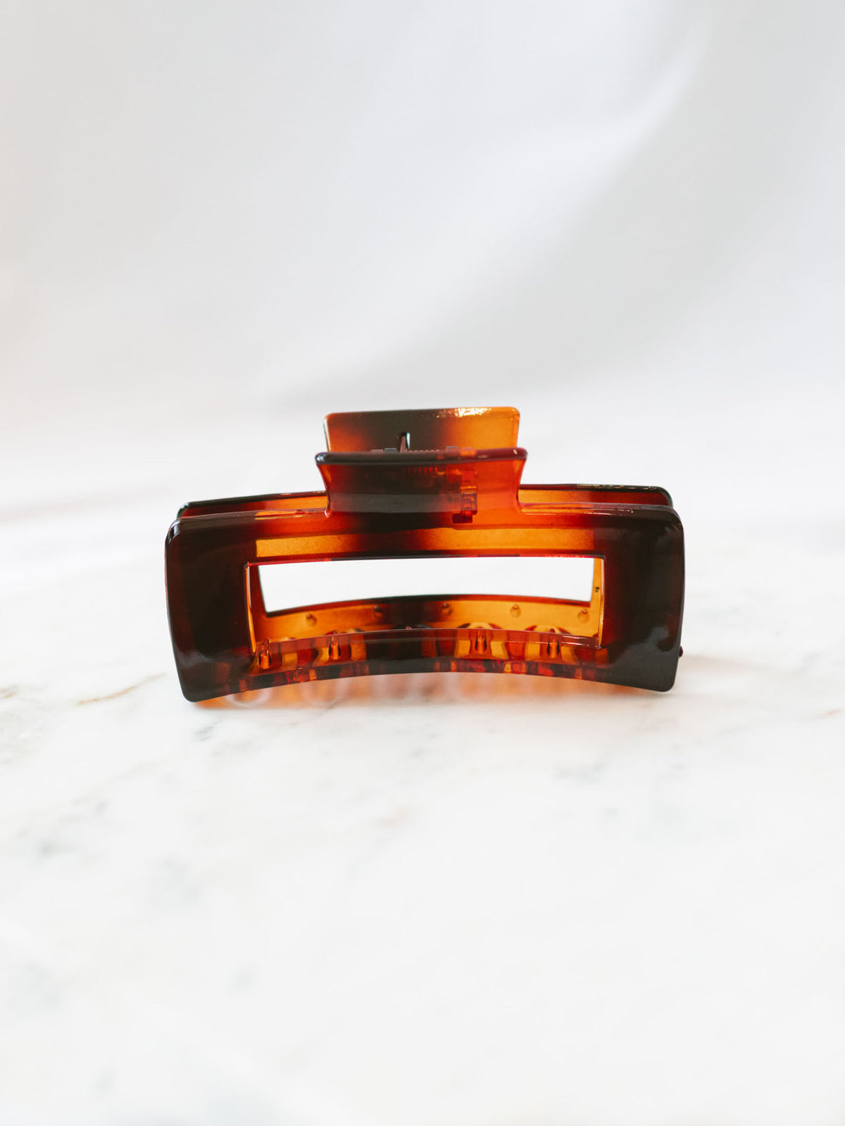 Brown square claw clip sitting on marble board. 