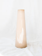 Narrow mouth tri color glazed artisan vase standing against a white linen backdrop. 