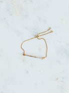 Montessa gold adjustable sparkle bar detail bracelet laying on marble board. 