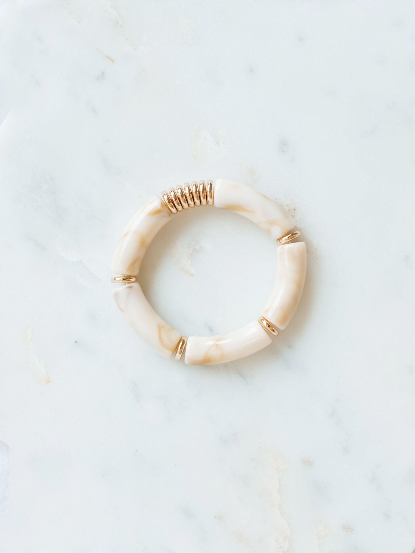 Cream chunky beaded stretch bracelet laying on marble board. 