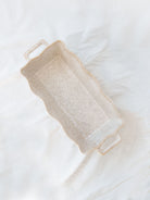 Beige scallop edge baking dish on white linen backdrop.