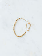 Gold beaded adjustable bracelet in medium size laying on marble board. 
