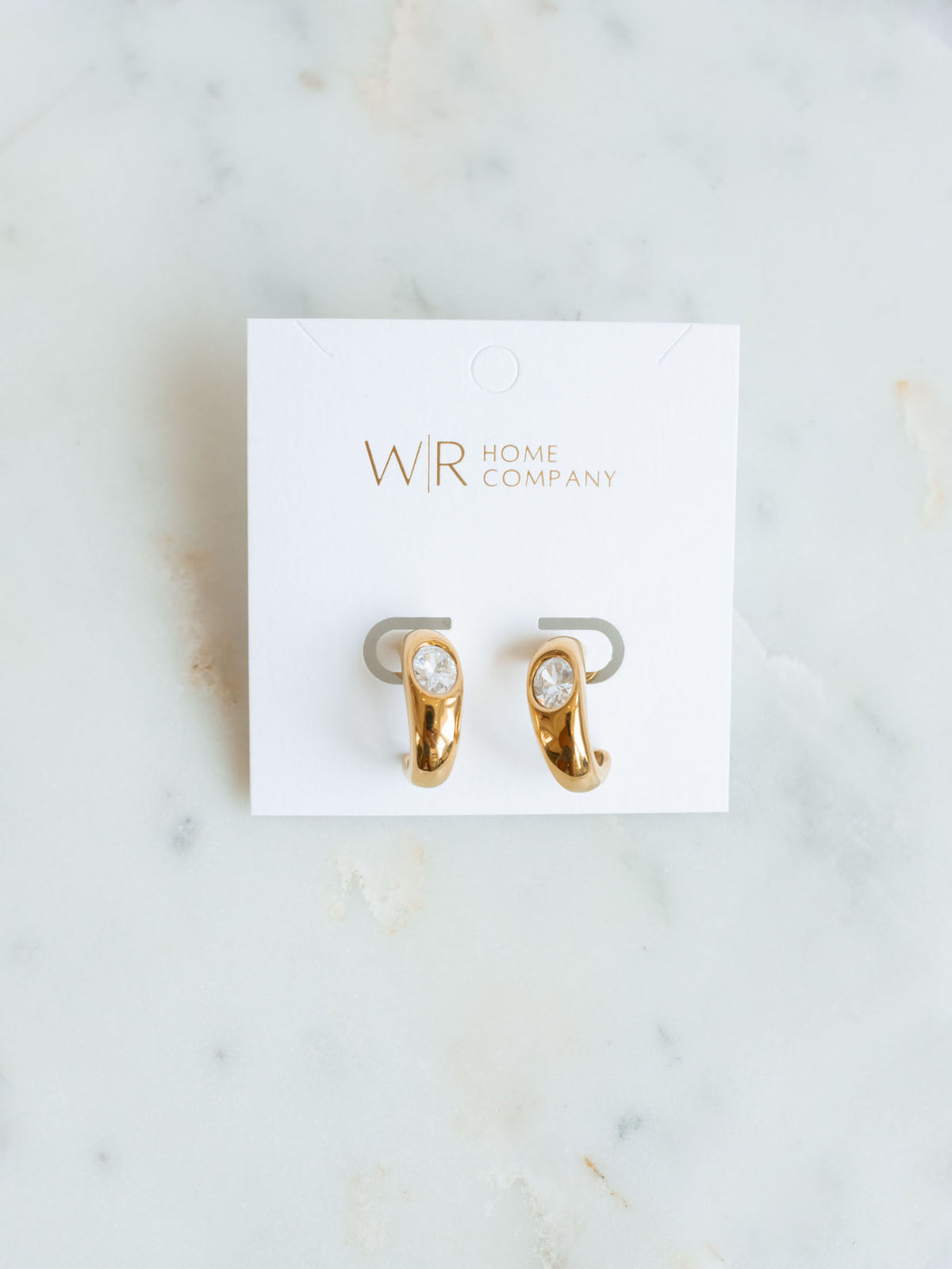 Gold hoops with CZ detail laying on marble board. 
