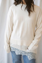 Traci cream knit long sleeve sweater top with a contrasting satin lace layered hem.
