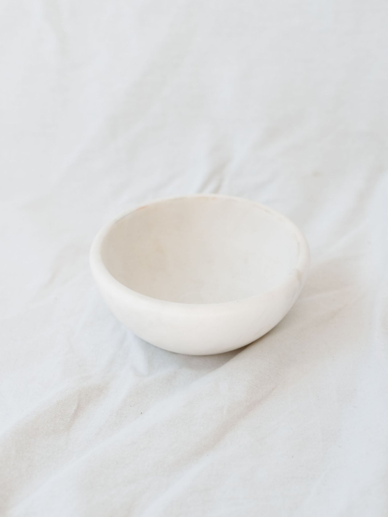 Large size of the marble bowls sitting in front of a white linen backdrop. 