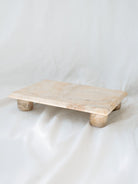 Side view of marble footed decorative riser sitting on white linen backdrop. 