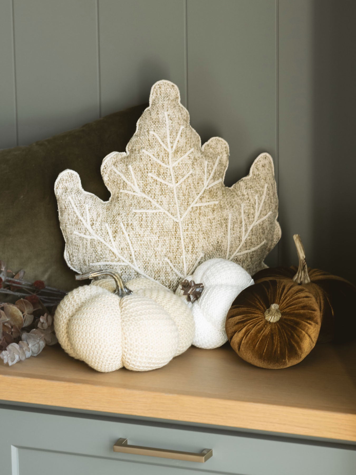 Tweed leaf shaped pillow styled on bench with other textured knit and velvet pumpkins, creating a beautiful full fall moment. 