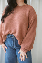 Model is wearing a round neck knit sweater featuring balloon sleeves 