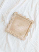 Top view of the 7.7" square cement scallop edge tray sitting on a white linen backdrop. 