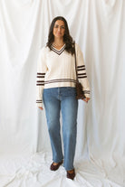Charlotte cream cable knit V-neck varsity sweater with chocolate brown accents and classic collegiate-inspired details.