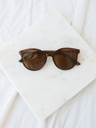 Tortoise round lens sunglasses laying on marble board. 